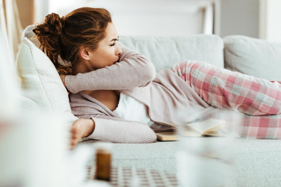 young-woman-coughing-into-elbow-while-lying-down-on-sofa-in-the-living-room (2)