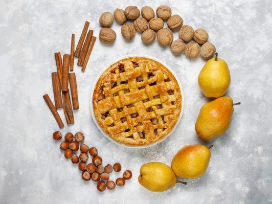 Homemade pear pie with cinnamon and walnuts on light background