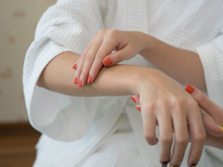 Young woman applying with finger white moisturizing cream on han